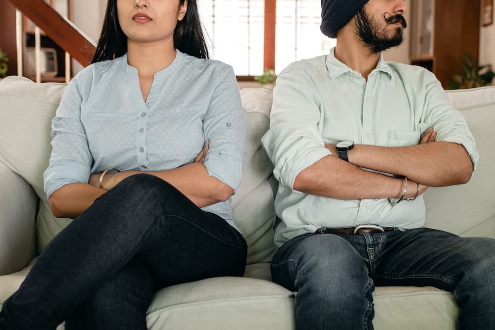 A couple sitting apart on a couch, turned away from each other